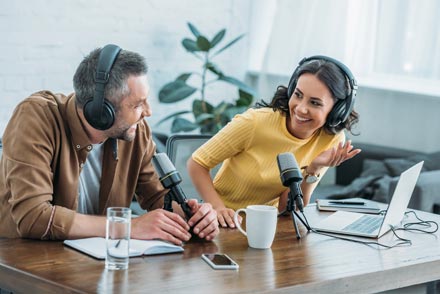 Two podcasters having a laugh in the studio. They will transcribe their podcast for better accessibility and SEO.