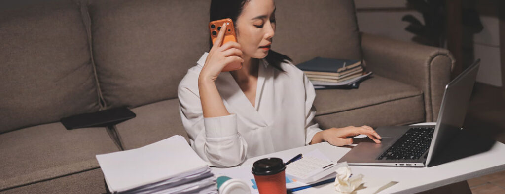 Woman on couch working overtime writing reports | Insurance Adjuster Transcription Services | Preferred Transcriptions